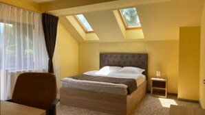 A hotel room with a bed, a desk, a chair, a nightstand, and skylights. - BELLESTAY/Suite for 4 (Brașov)