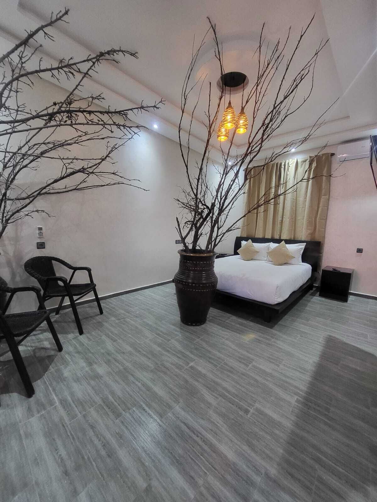 A modern bedroom with a bed, a large vase, and two chairs.