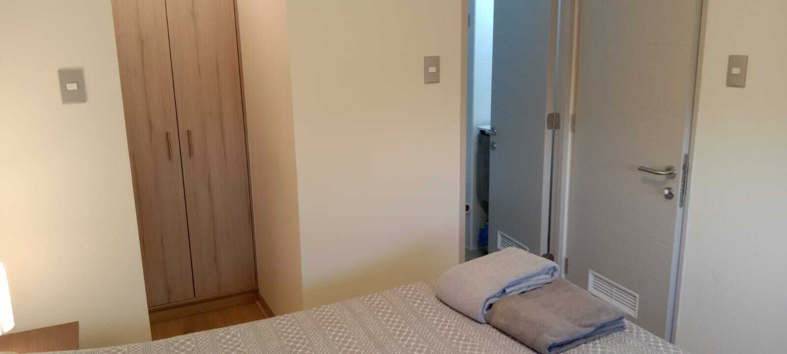 Ein Schlafzimmer mit einem Bett, einem Holzschrank und einer Tür zu einem Badezimmer.