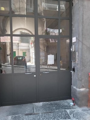Une porte double fermée, dont les panneaux de verre donnent sur une rue et des immeubles.