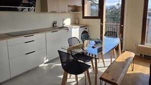Une cuisine compacte avec un coin repas, un banc et une vue à travers une porte.