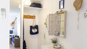 A compact hotel room with a bed, a small desk, a mirror, a radiator, and a door leading to another room. - Beautiful apartment with sea view and quiet (Sainte-Maxime)