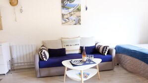 A room with a sofa, a small table with a bottle and glasses, a radiator, and a painting on the wall. - Beautiful apartment with sea view and quiet (Sainte-Maxime)