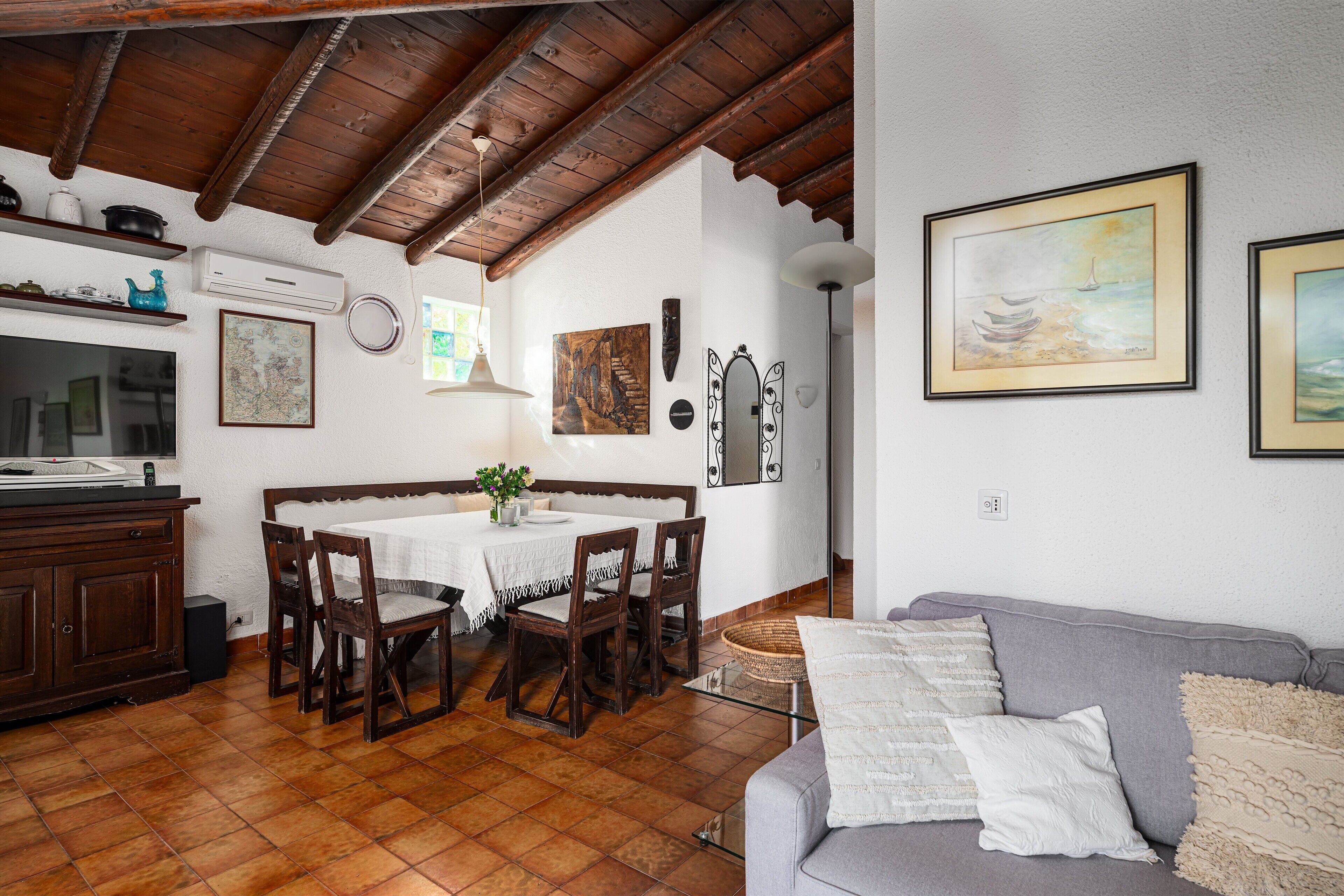 Un espace repas comprenant une table et des chaises, un canapé, ainsi qu’un coin cuisine avec des placards et une cuisinière.