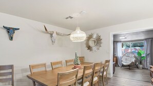 En matplats med ett träbord och stolar, en hängande lampa och dekorativ väggkonst.