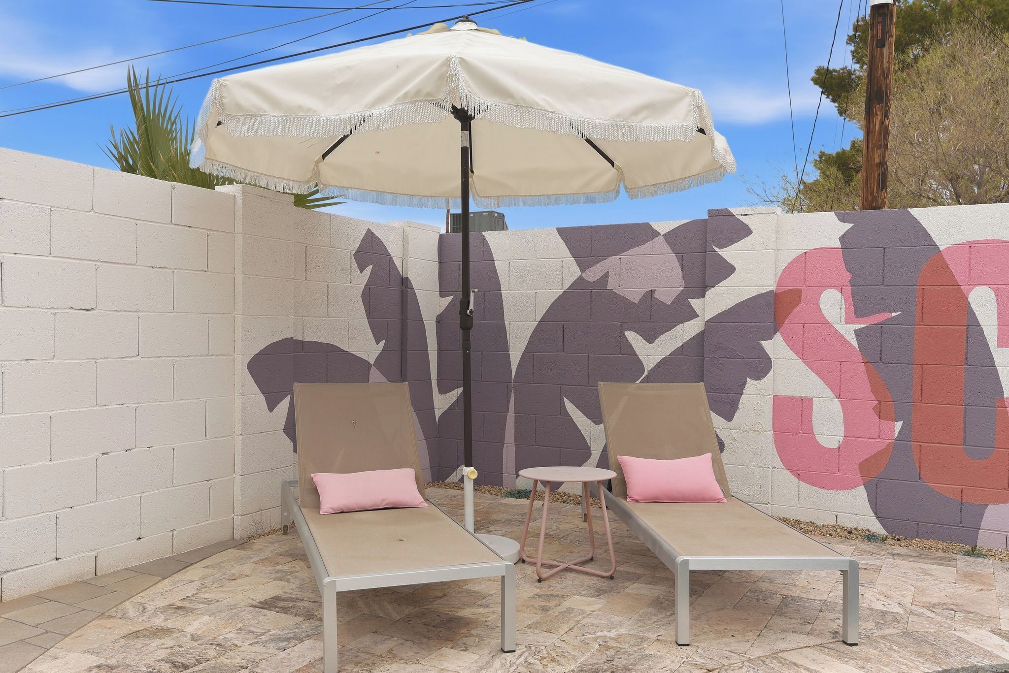 A patio with two lounge chairs, a small table, and a large umbrella.