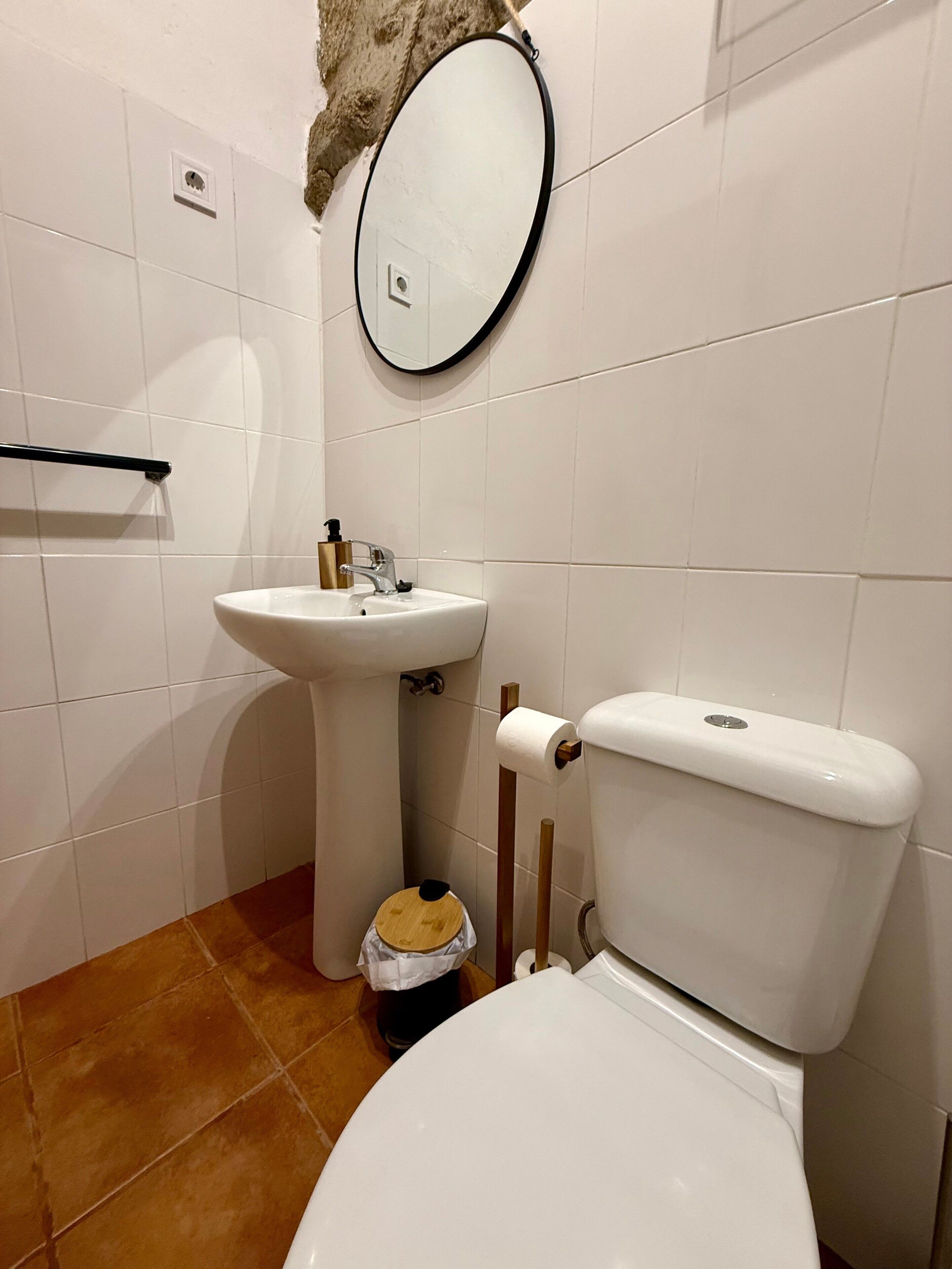 Un baño con inodoro, lavamanos y espejo.