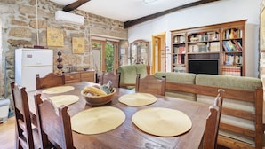 A rustic dining area with a wooden table, chairs, and a stone wall. - Casa Da Adega, between the Minho River and the Mountains (Sá)