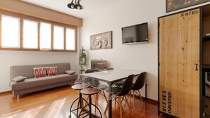 A dining area with a table, chairs, a sofa, and a TV. - GuestHost - Comfortable 60m2 apartment, ideal for 4, on the 4th floor of a building with lift (steps to reach it). Located in Fiera Milano City between Portello and CityLife, a historic exhibition area now transformed into the Allianz MiCo convention cen (Milan)
