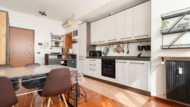 A modern kitchen with white cabinets, a dining table with chairs, and a built-in oven. - GuestHost - Comfortable 60m2 apartment, ideal for 4, on the 4th floor of a building with lift (steps to reach it). Located in Fiera Milano City between Portello and CityLife, a historic exhibition area now transformed into the Allianz MiCo convention cen (Milan)