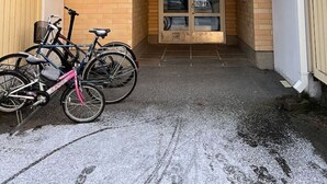 Un immeuble à plusieurs étages doté d’un balcon, avec un vélo garé devant et une porte donnant sur un espace intérieur.