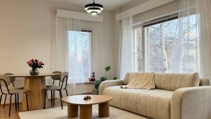 Un salon moderne comprenant un canapé, une table basse, une table à manger, des chaises et de grandes fenêtres.