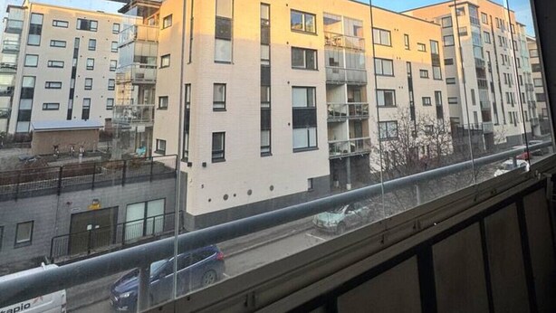 Ein mehrgeschossiges Gebäude mit einer glatten Fassade, großen Fenstern und einer belebten Straße mit Fahrzeugen.