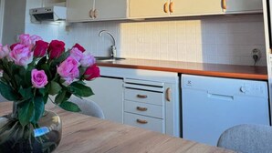 Eine Küche mit weißen Schränken, einer Holzarbeitsplatte, einem Spülbecken und einem Blumenstrauß auf dem Tisch.