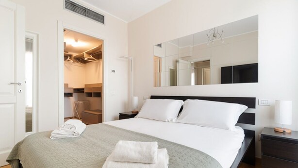 Une chambre d’hôtel comprenant un lit, une armoire, un miroir et une table de chevet.