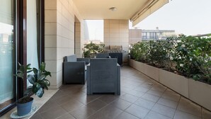 Un balcon aménagé avec du mobilier d’extérieur, un barbecue et des plantes en pot.