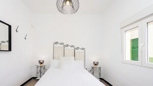 Ein Schlafzimmer mit Bett, Nachttischlampen, einem Spiegel und einem Fenster.