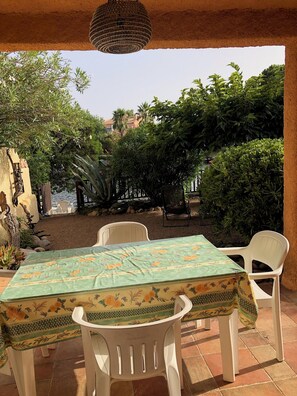 An outdoor patio with a table and chairs, surrounded by greenery and a view of a body of water. - Ferienhaus mit Zugang zum Meer (Lecci)