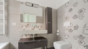 Un baño moderno con tocador, inodoro, bidé y un espejo sobre el lavamanos.
