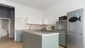 Una cocina moderna con una isla central, electrodomésticos de acero inoxidable y un pez decorativo en el refrigerador.