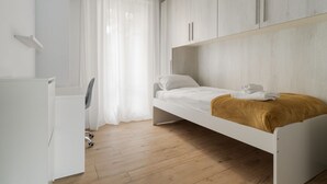 Un dormitorio minimalista con una cama, un escritorio y un armario.