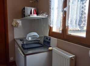 A compact kitchen with a dish rack, a kettle, and a microwave.
