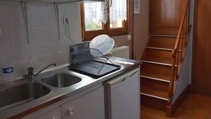Una cocina compacta equipada con lavavajillas, tetera y lavabo.