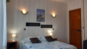 Un dormitorio con una cama, dos lámparas de pared, un cartel y una puerta de madera.