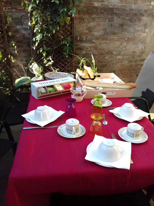 A table set for a meal with a red tablecloth, white plates, and a box of Clivita tea.