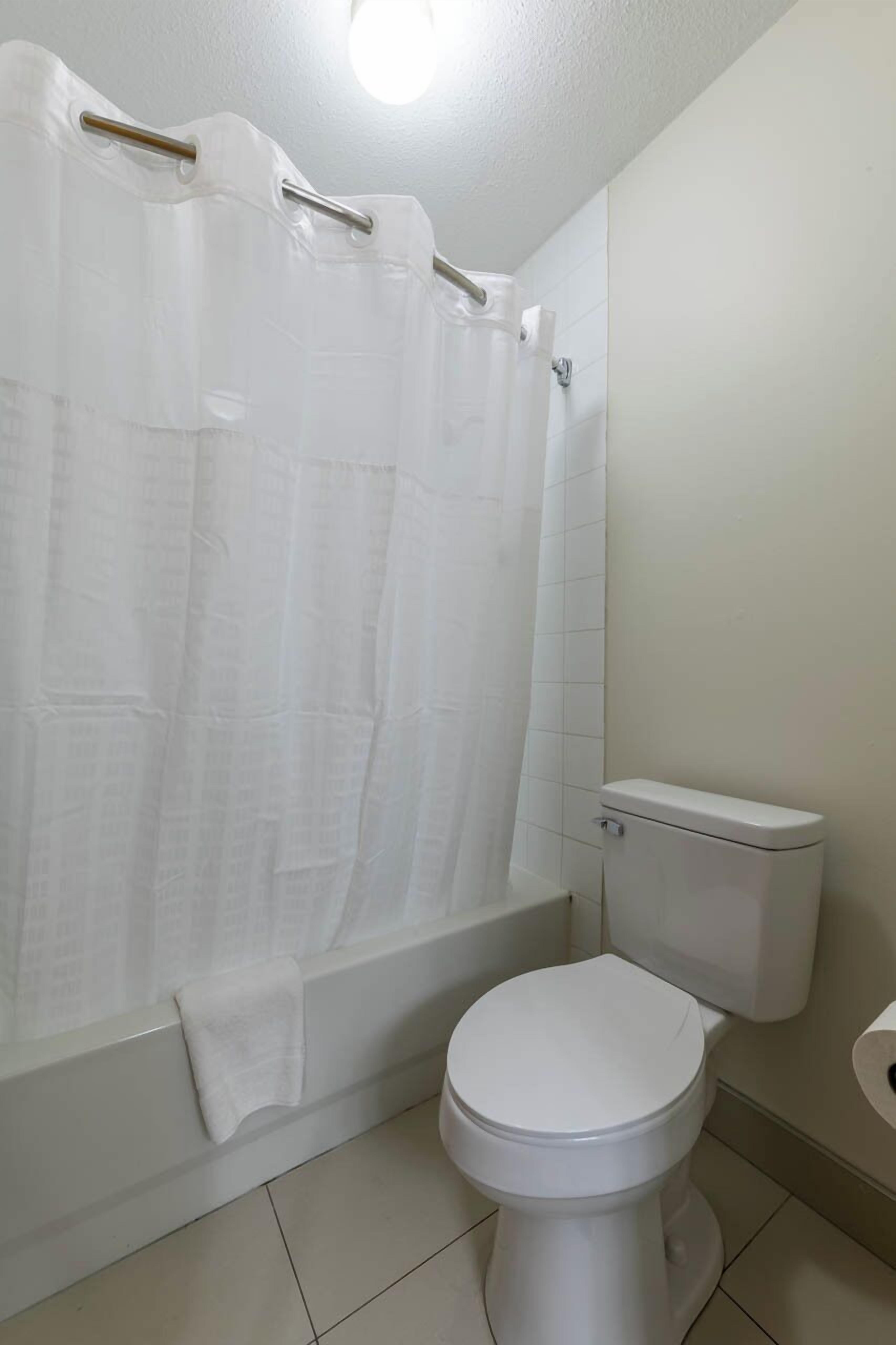 Un baño con inodoro blanco, bañera y cortina de ducha.