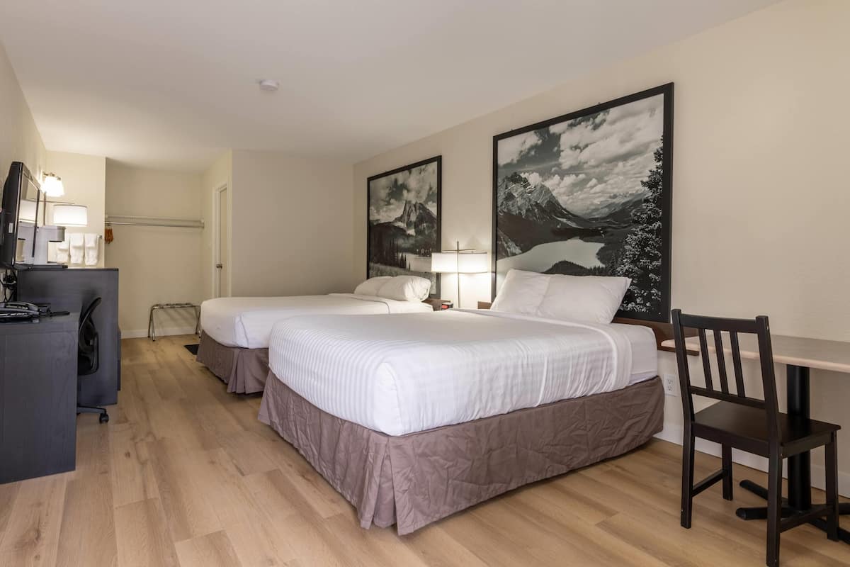 Een hotelkamer met twee bedden, een bureau en een stoel.
