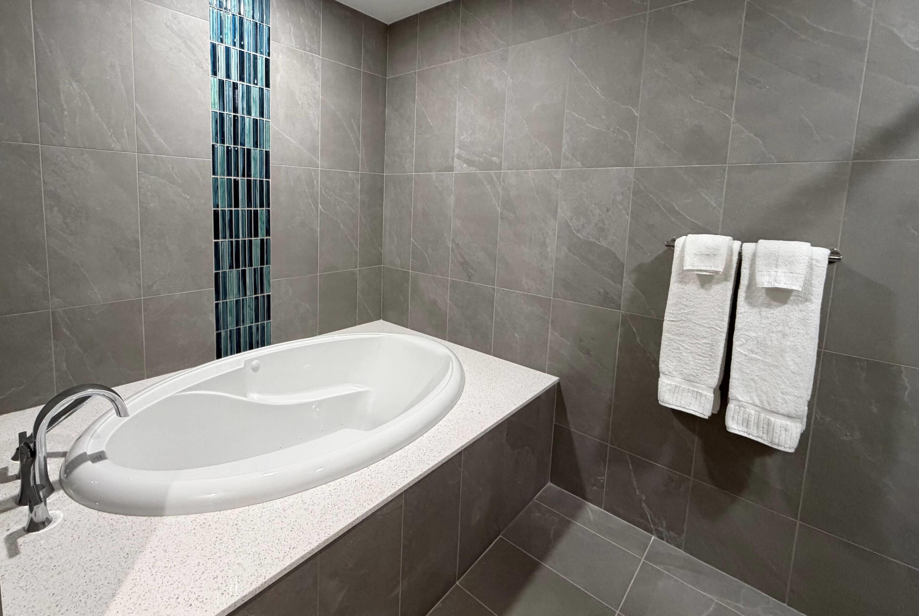 A bathroom with a bathtub, a sink, and two towels on a rack.
