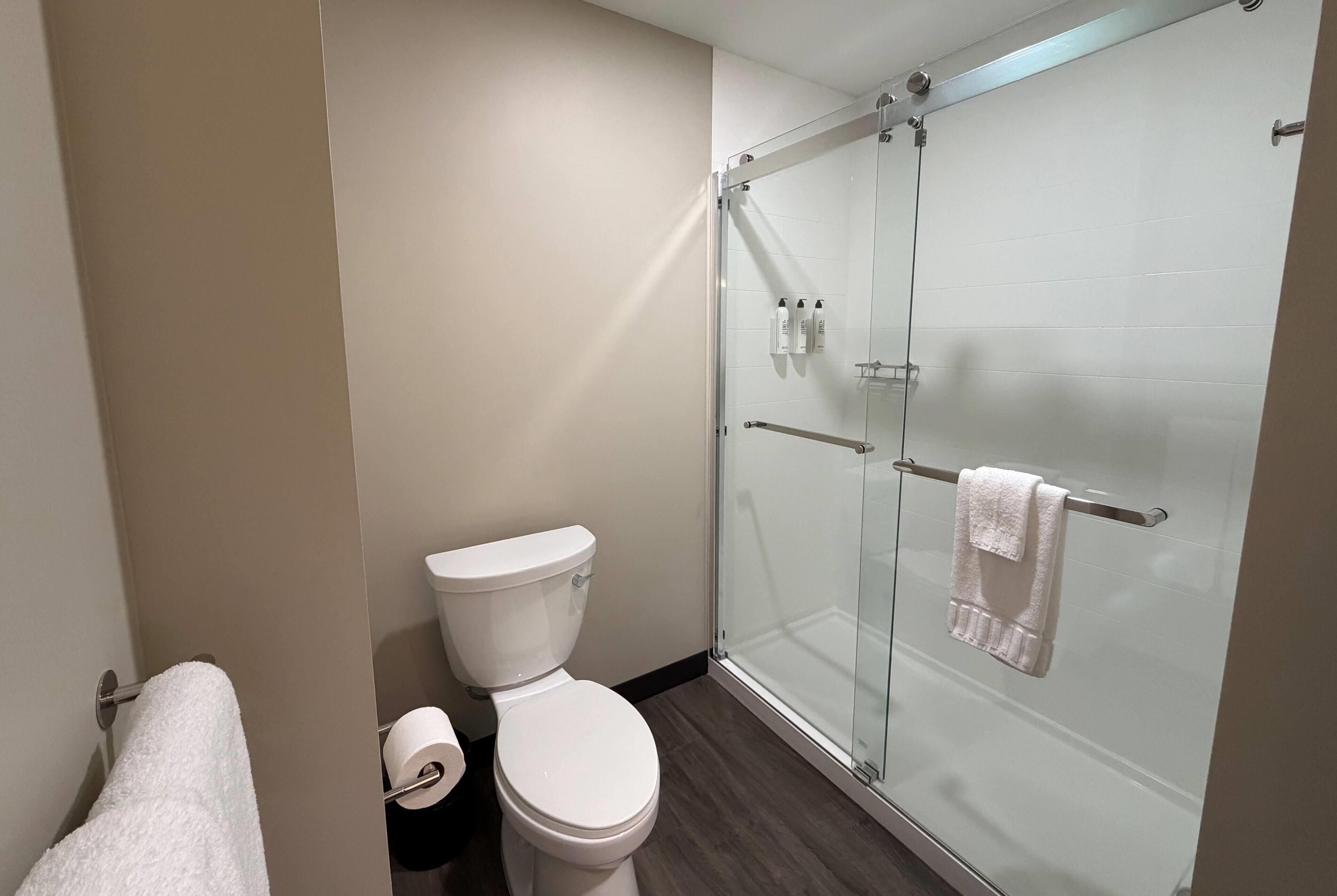 Une salle de bain équipée de toilettes, d’une douche à parois de verre et d’un porte-serviettes.