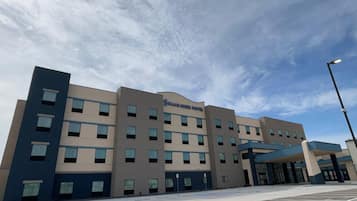 A multi-story hotel building with a flat facade, multiple windows, and a clear sky in the background.