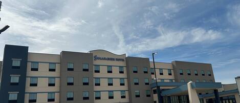 A multi-story hotel with a flat facade, large windows, and a prominent signage for 'Sugar Creek Hotel.'