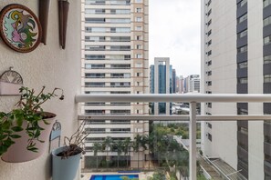A balcony with potted plants, a framed picture, and a view of high-rise buildings. - IA71 3 bedroom apartment Itaim 4p/3br (São Paulo)