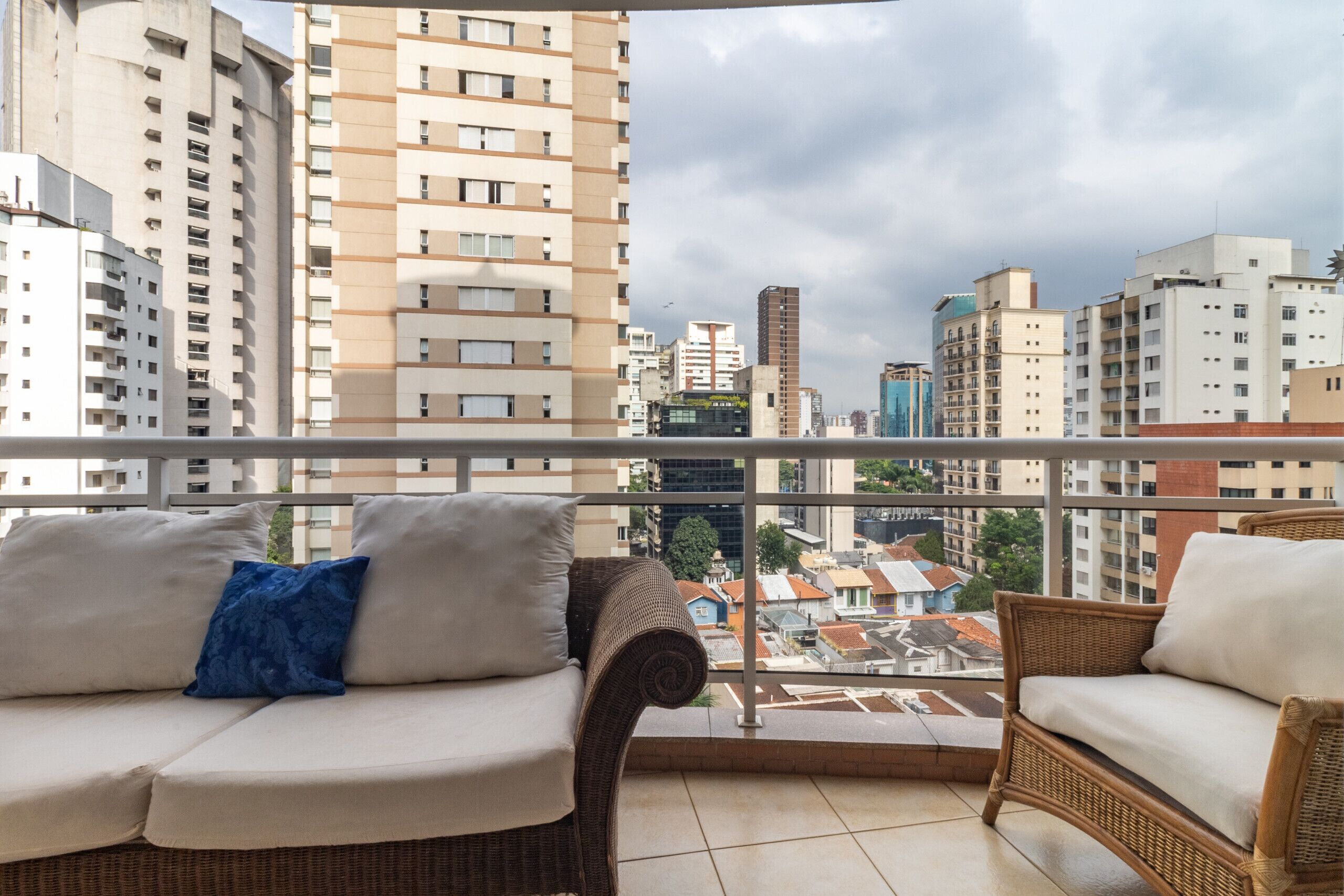 A balcony with wicker furniture and a city view.
