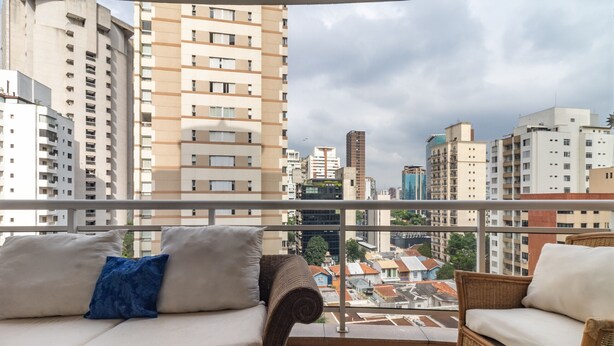 Een balkon met rieten meubilair en uitzicht op de stad.