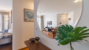 Een moderne woonkamer met een grote spiegel, een eethoek met een houten tafel en een potplant.