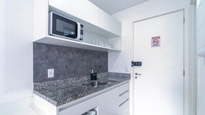 Une cuisine équipée d’un plan de travail en granit, d’un four à micro-ondes, d’un évier et d’une porte sur laquelle est apposé un panneau « Il est interdit de fumer ».