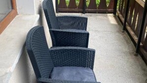 A set of wicker chairs with cushions on a concrete patio.
