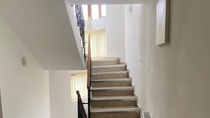 A staircase with a handrail, a radiator, and a window with blinds.