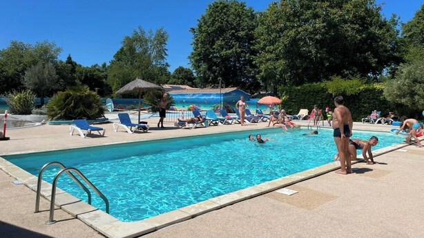 A swimming pool with lounge chairs and umbrellas, surrounded by trees. - 🌞 Air-conditioned mobile home 6 pers - Camping 3⭐ avec piscine - Landes - dès 70€/nuit (Sainte-Eulalie-en-Born)