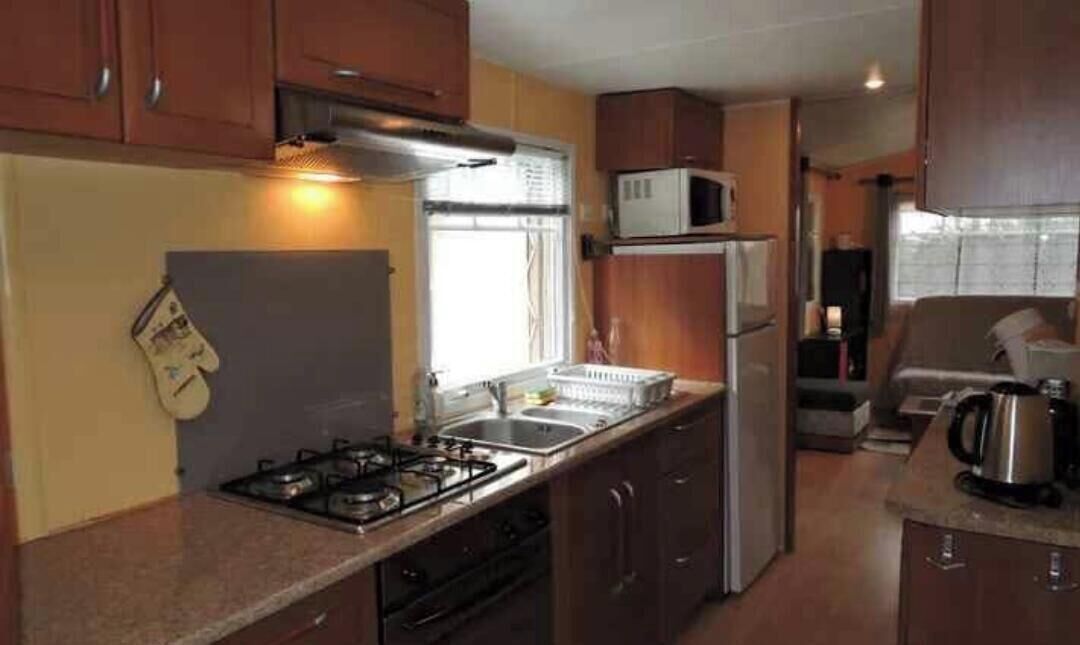 Une cuisine de taille réduite équipée d’une cuisinière à gaz, d’un évier, d’un four à micro-ondes et d’un réfrigérateur.