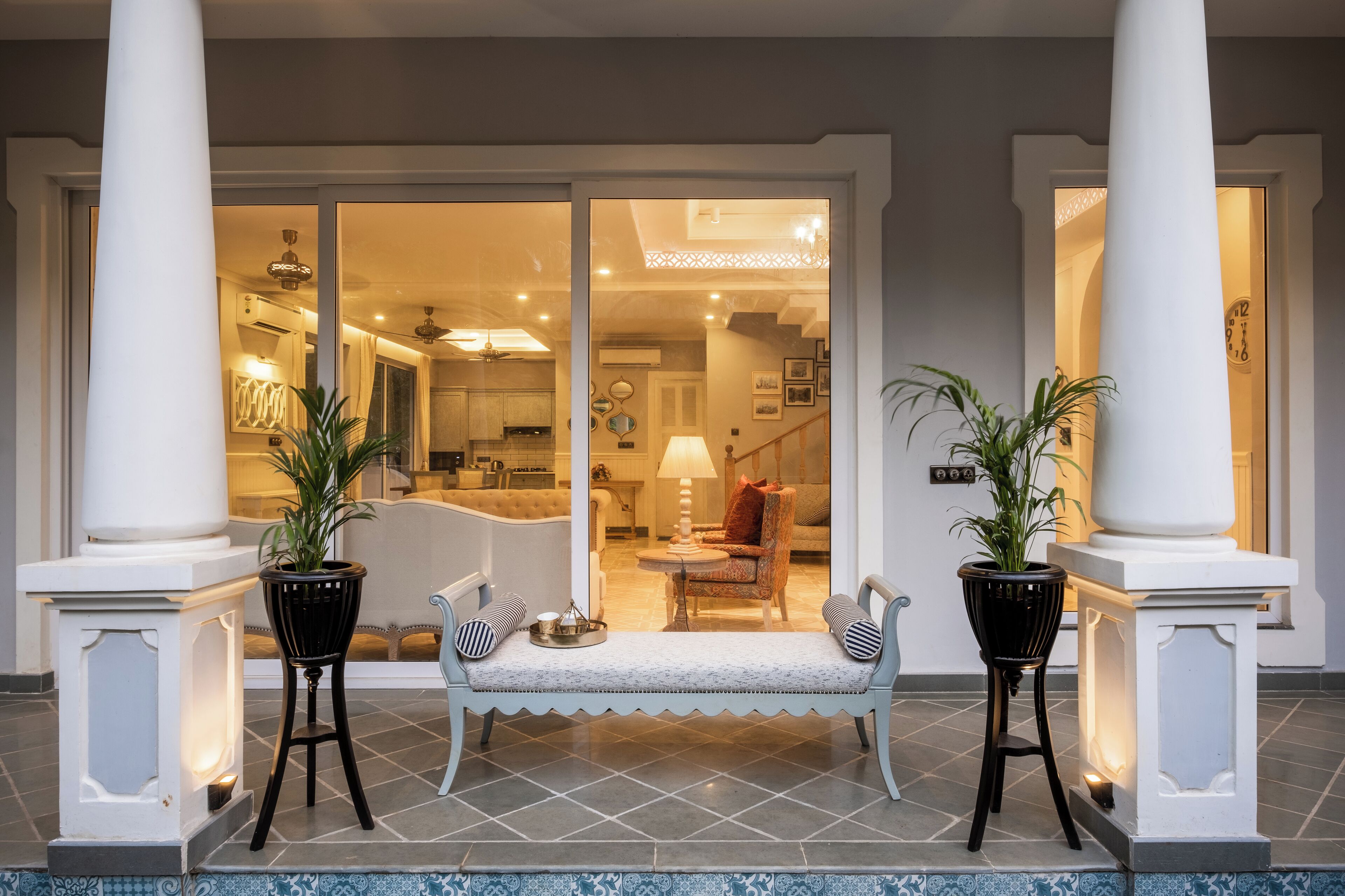 A hotel entrance with a bench, two potted plants, and a view into the interior.