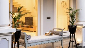 Un hall d’entrée bien éclairé, avec un banc, deux chaises et des plantes en pot.