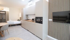 A modern kitchen with a dining area, a microwave, and a flat-screen TV. - Favara 1 by Concept Flats (Valencia)