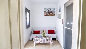 A small, cozy room with a white sofa, a coffee table with a floral tablecloth, and a framed picture of a deer on the wall. - Modern Holiday Home in Almeria With Pool (Pechina)