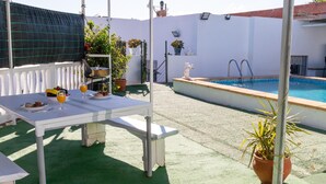 A poolside area with a table set for two, a small pool, and potted plants. - Modern Holiday Home in Almeria With Pool (Pechina)