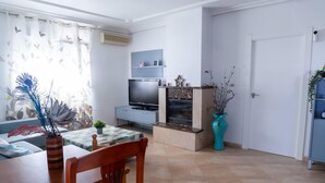 A living room with a TV, sofa, dining table, and a fireplace. - Modern Holiday Home in Almeria With Pool (Pechina)
